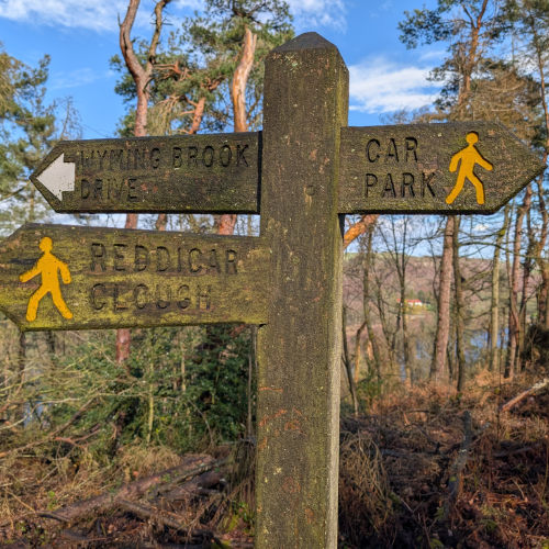 Wooden sign pointing to Car Park to the right and Wyming Brook Drive and Reddicar Clough to the left